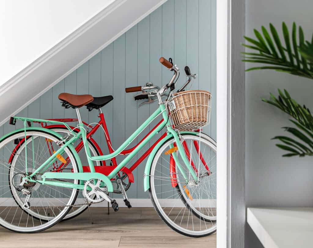 Red and aqua reid roadster bikes are located under the stairs at Silvermere Retreat Coastal Culburra Beach South Coast NSW. The bikes are free for guests to use.
