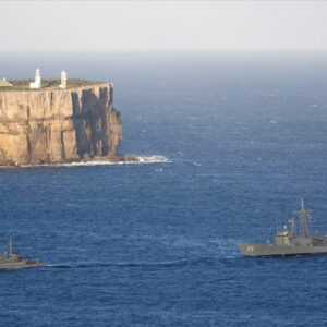 Beecroft Weapons Range and Peninsula is located not far from Culburra Beach on South Coast NSW. Image of a lighthouse and the ocean with one large navy boat and a smaller vessel.